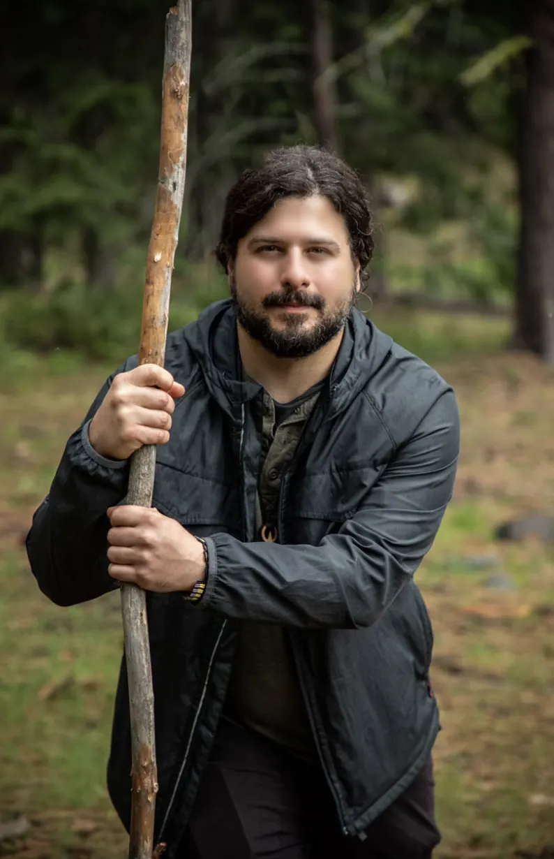 Mike Brancatelli holding a wooden staff in the forest